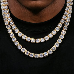 10MM Cushion Clustered Tennis Chain in Gold layered double‑stack wearing shot on deep skin clean‑shaven male model in plain black crew neck t‑shirt, two staggered length icy hip‑hop necklaces stacked together, hand‑set cushion halo VVS simulated diamond links, brilliant sparkling starburst stone reflections, thick gold‑plated unisex rap‑style statement jewelry lifestyle product photo RDRIP JEWELRY