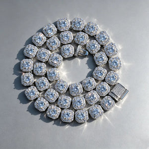 10MM Cushion Clustered Tennis Chain in White Gold top‑down overhead shot, fully coiled cushion cluster tennis necklace with fully iced out box clasp, VVS simulated diamond links, icy bling unisex hip hop jewelry laying flat on seamless edge‑free grey reflective board, sparkling brilliant stones men women statement necklace RDRIP JEWELRY