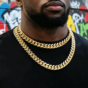 12.2mm wide 18k gold plated classic Miami Cuban link choker with sturdy box clasp, two layered stackable hip hop gold curb chains worn by Black man with trimmed beard, black plain tee, vibrant colorful street graffiti wall backdrop, heavy thick tight interlocking cuban links, shiny polished gold finish anti tarnish men streetwear jewelry, premium hip hop stack necklace for everyday wear, RDRIP JEWELRY SINCE 2016