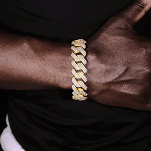 Front view shot of male dark skin hand wearing 19mm Full Iced Out Prong Cuban Link Bracelet with premium 18K gold plating, solid copper base fully encrusted with lab-tested flawless VVS simulated diamonds, brand-new upgraded prong setting craft with full diamond coverage on every link, heavy oversized hip hop streetwear bling wrist jewelry matched with plain black casual top background, tarnish resistant unisex diamond cuban bracelet for men statement accessory RDRIP JEWELRY