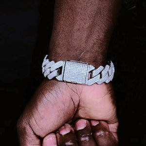Close-up shot of a man’s dark skin hand showcasing 19mm full iced out prong cuban link bracelet with fully diamond encrusted box clasp, every link secured with hand-set prong lifted flawless VVS lab-verified simulated diamonds, premium 18K white gold plated solid copper heavy hip hop bling wrist chain, unisex bold streetwear statement jewelry with ultra-bright icy shine, scratch & tarnish resistant everyday wear cuban bracelet RDRIP JEWELRY