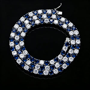 4MM alternating blue sapphire and clear moissanite tennis chain coiled on deep black background, 925 sterling silver white gold plated setting, round‑cut deep blue sapphire simulants paired with brilliant clear moissanite stones, iced‑out two‑tone hip hop statement necklace close‑up studio shot RDRIP JEWELRY