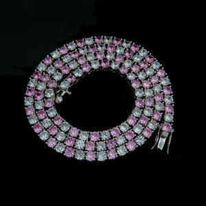 4mm Aurora Rainbow Iced Tennis Chain coiled full overhead view, pastel pink purple blue ombré gradient VVS CZ simulated diamonds, hand prong‑set stones, metal lock clasp detail, 18K gold plated unisex hip hop bling necklace against solid black background, RDRIP JEWELRY