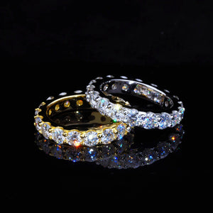 6.00 CARAT S925 VVS1+ moissanite single‑row full eternity ring, 4mm round ideal cut hearts and arrows moissanite stones, interlaced display of 18K gold‑plated and white gold‑plated 925 sterling silver bands, two rings overlapping on glossy black reflective surface, brilliant rainbow light dispersion, dark studio product close‑up shot, icy sparkling full circle band, unisex hip‑hop wedding matching stackable fine bling jewelry RDRIP JEWELRY