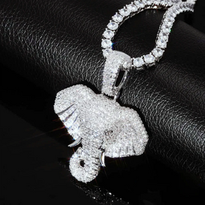 Extreme close‑up shot of iced micro paved pharaoh elephant head pendant, silver finish fully set with AAA cubic zirconia stones, paired with sparkling tennis chain, brilliant stone sparkle on textured black leather surface, premium hip hop bling charm for men RDRIP JEWELRY