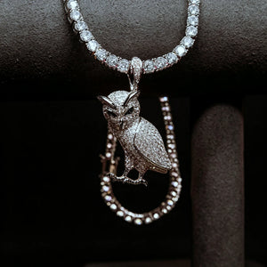 Iced Out Full Pave 3D Owl Pendant hanging on necklace display stand, full micro pave cubic zirconia owl charm matched with tennis chain, blurred tennis chain on dark pure black background, men hip hop bling animal pendant street jewelry RDRIP JEWELRY