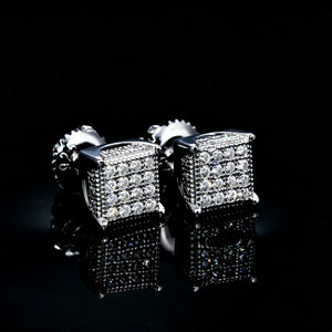 S925 Silver VVS Moissanite Micro Pave Border Cube Stud Earrings, paired front view of 3D fully iced cube earrings with screw back, hip hop square stud jewelry on reflective black surface, RDRIP JEWELRY