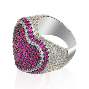 Side profile angled shot of magenta pink iced out pave love heart ring, showing polished smooth inner band, full micro hand‑set AAA cubic zirconia stones, two‑tone pink and clear CZ pave detailing, thick wide heavy‑set hip hop statement heart ring, isolated white studio background, unisex bling rapper fashion jewelry for men and women RDRIP JEWELRY