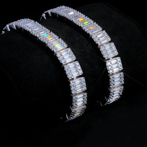 Slanted studio display shot of two 8mm rectangular baguette cut VVS1+ D color moissanite tennis bracelets resting on soft black velvet cushion, crafted from solid S925 sterling silver with dual plating options of polished white gold and 18K gold, every rectangular baguette moissanite surrounded by round brilliant moissanite hand prong set by skilled artisans, brilliant rainbow light fire and icy diamond-like sparkle, scratch and tarnish resistant daily wear hip hop street stacking wrist jewelry for men