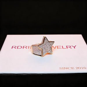Angled product shot of gold plated iced out pentagram wide band hip hop ring with full micro paved cubic zirconia stones resting on branded gift box, 3D star icy bling men statement jewelry for streetwear and rap fashion RDRIP JEWELRY