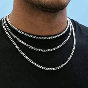 Close-up neck shot of Black male model with ultra-short stubble beard wearing three layered stackable polished 3mm white gold Italian Franco link chain necklaces, flexible tangle-resistant Franco curb chain for men hip hop streetwear fashion, premium anti-tarnish stainless steel unisex minimalist layering jewelry, sleek thin hand-finished Franco chain available in 18 inch and 20 inch lengths, lightweight shiny everyday statement necklace, can be worn alone or layered with custom hip hop pendants