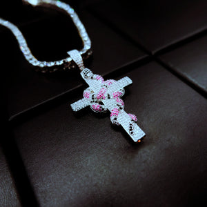 diagonal angle shot silver tone iced out coral snake wrapped cross pendant with bling tennis chain micro‑set pink black cubic zirconia serpent cross hip hop men necklace shot on dark leather background streetwear jewelry RDRIP JEWELRY