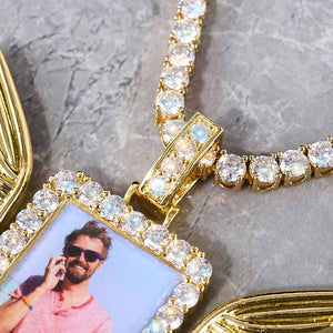 Iced Out Wings RIP Custom Photo Pendant, gold tone close-up detail shot, focus on stone frame, photo inset and iced bail, partial angel wings visible, matching tennis chain, grey marble texture background, memorial personalized hip hop photo jewelry detail view, RDRIP JEWELRY