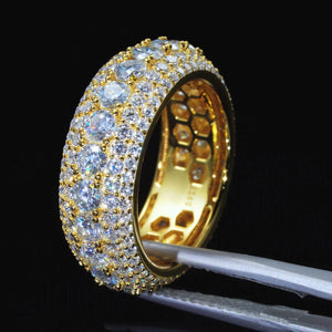 Angled studio shot of men’s 9mm wide multi‑layer full pave iced‑out moissanite eternity band RDRIP JEWELRY SINCE 2016, ring held by metal jewelry tweezers against pure black background. 18K gold plated solid 925 sterling silver band with inner honeycomb hollow construction, hand‑set 4mm D‑Color VVS1 hearts and arrows round moissanite stones, gold bead prong setting, brilliant sparkle, premium hip‑hop bling men’s statement jewelry