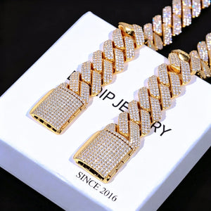 Flat lay studio shot of two 19mm Full Iced Out Prong Cuban Link Bracelets with premium 18K gold plating laid on clean white branded gift box printed with RDRIP JEWELRY and SINCE 2016, each cuban link and wide full iced box clasp densely set with lab-tested flawless VVS simulated diamonds, upgraded handcrafted prong setting craft, solid copper core heavy hip hop bling wrist jewelry set for men, bright icy diamond sparkle against pure black background, luxury unisex streetwear diamond cuban bracelet gift set