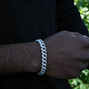 Front wrist close up of men's 10.5mm full iced out white gold plated cuban link bracelet, custom molded copper hip hop wrist jewelry with hand-set prong-lifted flawless VVS simulated diamonds, dark skin male model wearing icy miami cuban bracelet, natural lush green foliage plant background, heavy bling streetwear rapper accessory, available in 7", 8", 9" lengths, weight varies +/-5 grams, premium shiny diamond encrusted bracelet gift for hip hop fans, tarnish resistant fashion statement wrist chain, RDRIP 