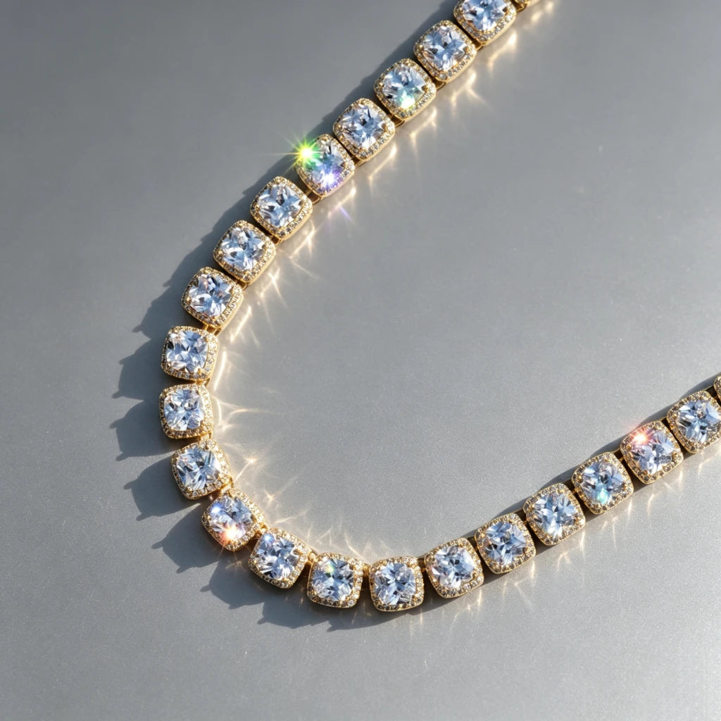10MM Cushion Clustered Tennis Chain in Gold lay‑flat angled product shot on seamless grey reflective surface, sunlit natural lighting, brilliant starburst sparkles and rainbow light flares, hand‑set cushion halo VVS simulated diamond links, thick gold‑plated hip‑hop bling necklace, unisex statement jewelry, realistic studio product photography RDRIP JEWELRY
