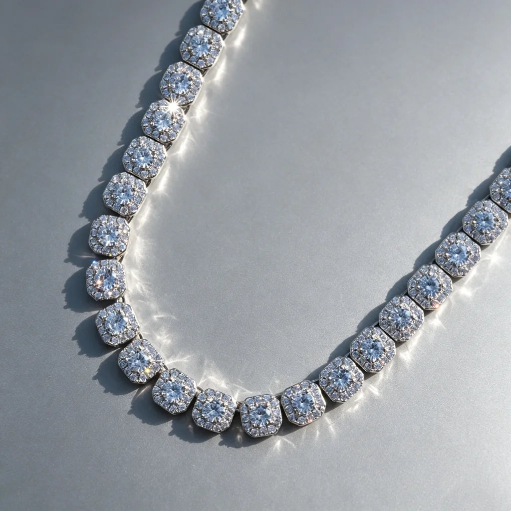 10MM Cushion Clustered Tennis Chain in White Gold close‑up detail shot, VVS simulated diamond cushion cluster links, icy bling hip hop unisex necklace lying flat on seamless grey reflective board, sparkling diamond highlights, premium men women statement bling jewelry RDRIP JEWELRY
