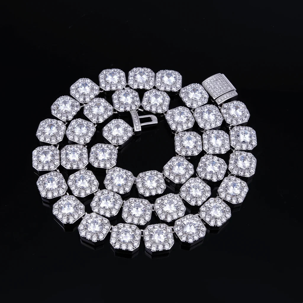 10MM Cushion Clustered Tennis Chain in White Gold top‑down overhead coiled layout, cushion cluster VVS simulated diamond links with fully iced encrusted box clasp, sparkling brilliant bling stones, laid flat on seamless black reflective board, luxury hip‑hop unisex statement neck chain for men and women RDRIP JEWELRY

