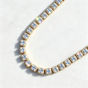 Flat‑lay top‑down product shot of 10MM Glacier Cushion Clustered Tennis Chain in 18K Gold, icy VVS cushion‑cut simulated diamond clustered tennis chain with brilliant sparkling stone reflections, hand prong‑set hip hop bling necklace displayed on subtle textured pure white marble background, premium unisex statement ice jewelry RDRIP JEWELRY

