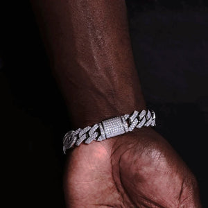 12mm Prong Set Iced Baguette Curb Bracelet White Gold Plated held on dark skin male palm closeup view, fully iced out covered clasp with flawless VVS rectangular baguette simulated diamonds, handmade prong setting thick wide curb link wrist chain, shiny icy bling hip hop streetwear jewelry for men, heavy duty mens diamond curb bracelet with full stone encrusted lock RDRIP JEWELRY
