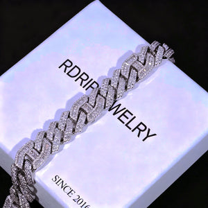 12mm Prong Set Iced Baguette Curb Bracelet White Gold Plated diagonal angle shot resting on branded RDRIP white jewelry gift box, hand prong set rectangular VVS simulated baguette diamond thick curb link bracelet, fully iced out bling cuban wrist chain with full stone coverage, luxury hip hop men's jewelry gift display, shiny reflective icy streetwear accessory perfect for gift giving RDRIP JEWELRY

