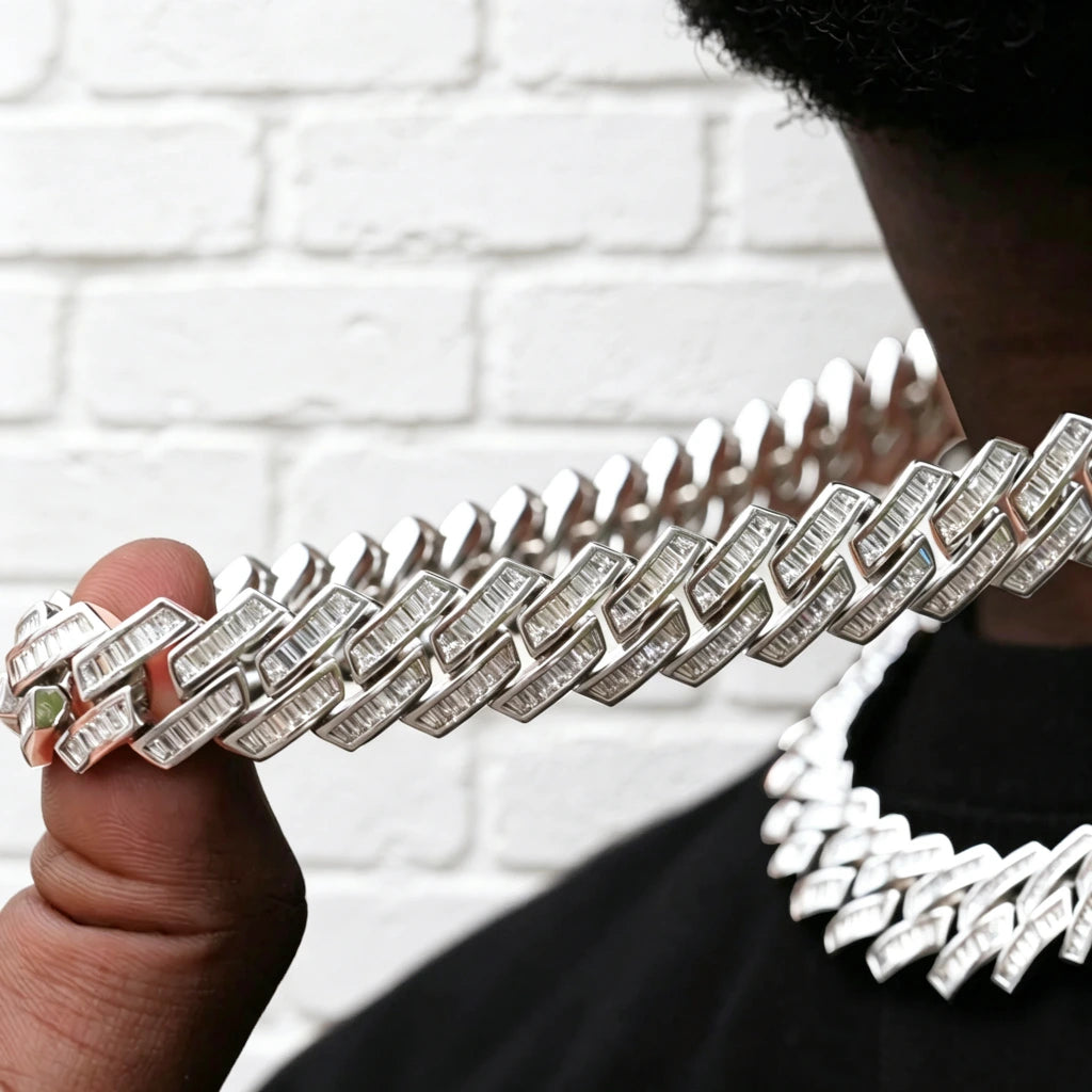 14MM Baguette Channel‑Set Miami Cuban Link Necklace held in male hand, 18K white gold plated iced‑out hip hop chain, hand‑set flawless VVS simulated baguette stones, close‑up view of channel‑set cuban links and stone brilliance, blurred necklace on model in background, clean white brick wall backdrop, premium bling rapper streetwear jewelry RDRIP JEWELRY
