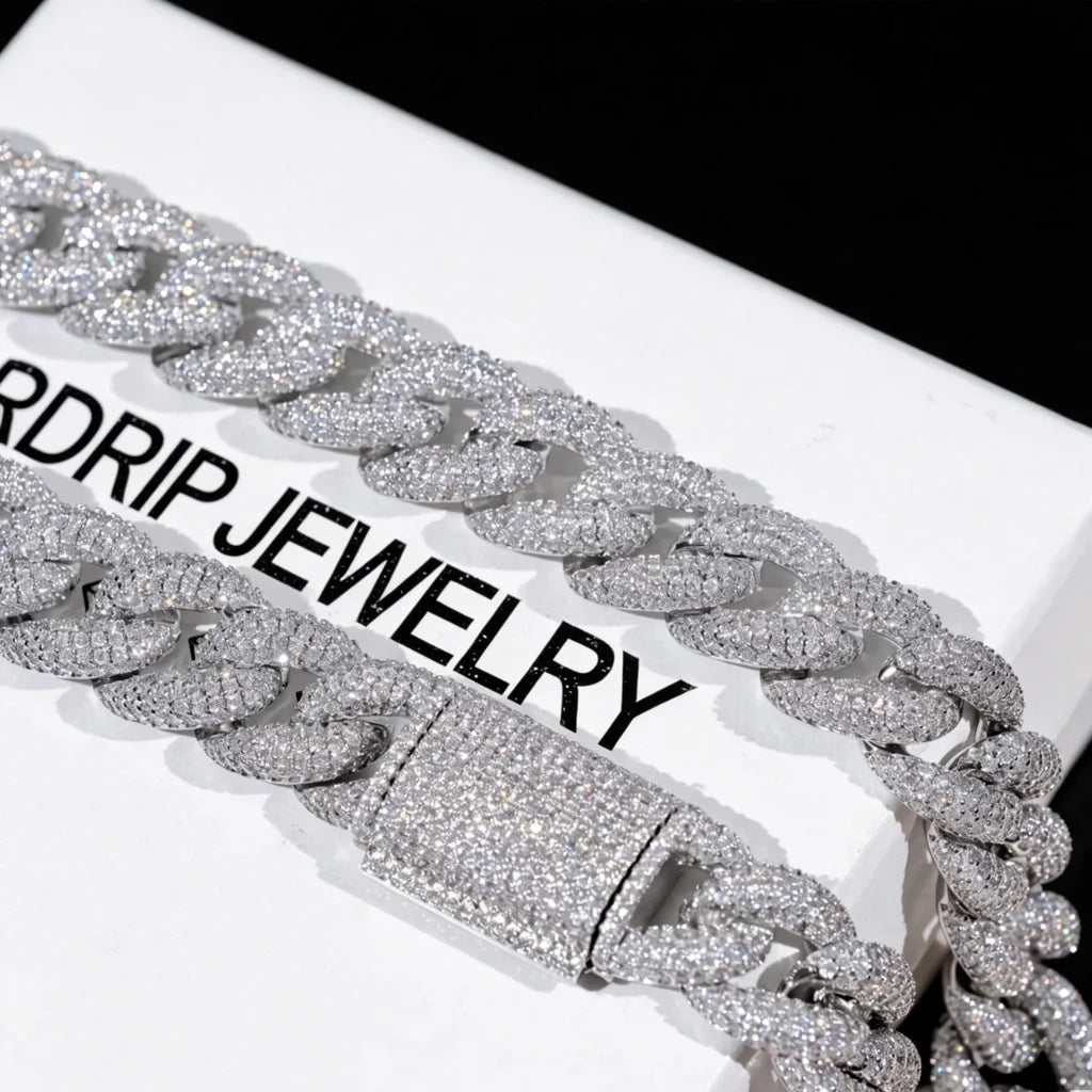 Close up shot of 15mm 5-Row Fully Paved Iced Cuban Link Necklace with fully iced out prong-set clasp, flawless VVS simulated diamond stones all over chain and lock, silver 18K white gold plated heavy Miami cuban chain laid on branded white jewelry box printed RDRIP JEWELRY, solid pure black background, premium handcrafted hip hop bling men's rapper jewelry available in 18 20 24 inch lengths RDRIP JEWELRY
