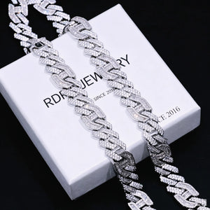 Angled partial close‑up shot of two 15mm prong‑set baguette mixed‑stone iced cuban curb chains in white gold finish, resting atop branded RDRIP JEWELRY gift box printed with SINCE 2016, hand‑set VVS simulated baguette cut and round diamonds, heavy full‑iced curb link details, dark textured black surface background, premium men hip‑hop streetwear bling statement necklace RDRIP JEWELRY
