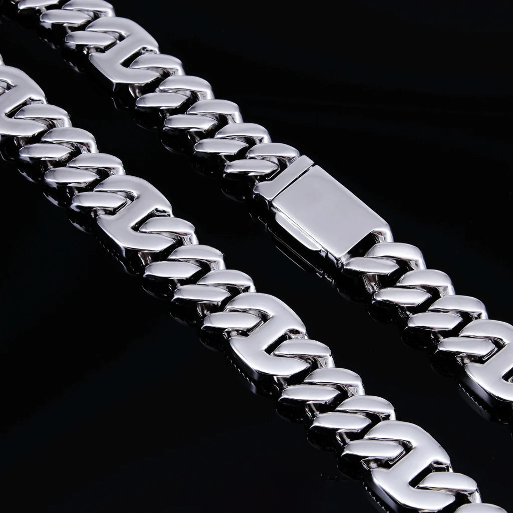 Macro close‑up hardware shot of 15mm prong‑set baguette mixed‑stone iced cuban curb chain in white gold finish, displaying polished solid box safety clasp and smooth curb link structure, high‑gloss reflective metal surface against deep solid black background, premium heavy‑duty hip‑hop men necklace locking mechanism detail shot RDRIP JEWELRY

