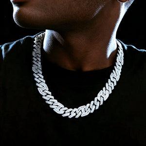 Neck close‑up shot of 15mm prong‑set baguette mixed‑stone iced cuban curb chain in white gold finish, worn by dark‑skin Black man with very short stubble beard, model wearing plain black t‑shirt against deep dark studio background, hand‑set VVS simulated diamonds full iced‑out heavy hip‑hop men necklace, premium streetwear bling jewelry RDRIP JEWELRY
