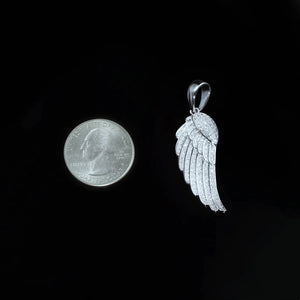 Size comparison view of 15mm Iced Micro‑Paved Single Seraph Wing Pendant in silver tone placed next to US quarter coin for scale reference, fully micro paved cubic zirconia feather wing charm against solid black background, RDRIP JEWELRY
