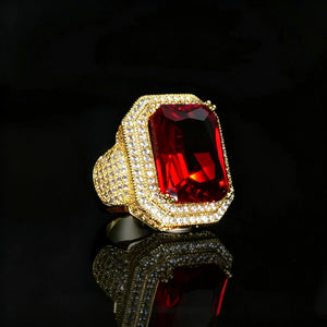 Men's heavy iced‑out hip‑hop statement ring, large emerald‑cut vivid red gemstone centerpiece, double halo hand‑set micro pave shimmering stones, premium 18K gold plated wide chunky band, luxury bling urban fashion jewelry for men, black background product shot with reflective surface RDRIP JEWELRY
