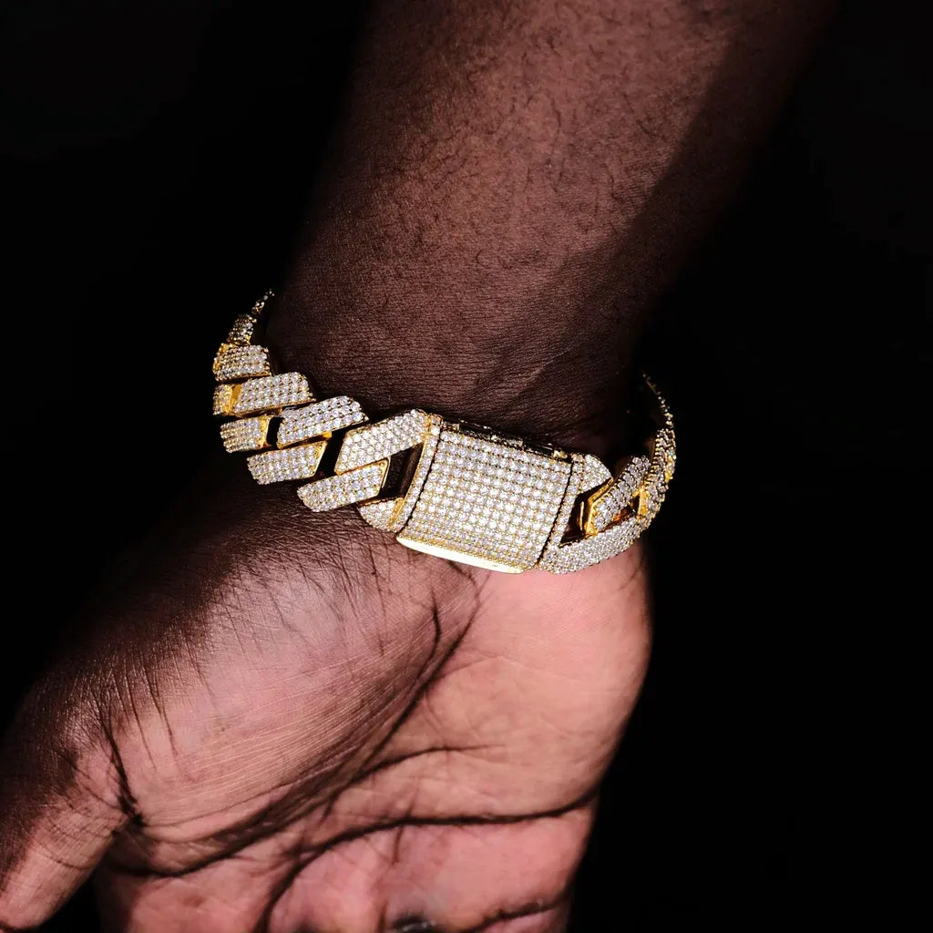 Studio close-up photo of 19mm Full Iced Out Prong Cuban Link Bracelet in premium 18K gold plating resting on dark skin male palm, featuring fully encrusted wide box clasp covered with flawless lab-tested VVS simulated diamonds, upgraded brand new prong setting craft with every cuban link fully iced, solid durable copper base handcrafted to perfection, heavy bold hip hop streetwear bling wrist accessory for men, reflective icy diamond shine against pure black minimalist background, tarnish resistant unisex s