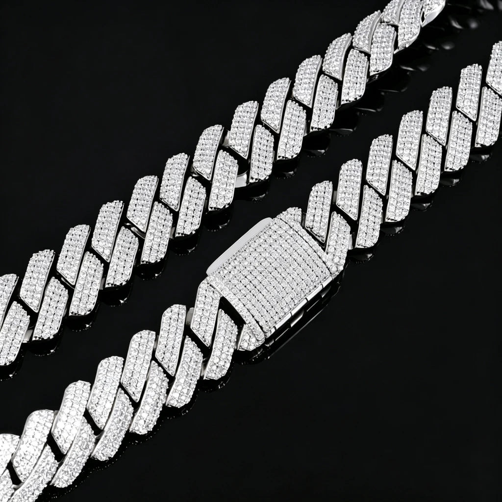 Top-down studio closeup of 19mm full iced out prong set rectangular baguette cuban link chain in polished 18K white gold finish, heavy hip hop necklace fully encrusted with flawless VVS simulated diamond stones, featuring fully micro pave iced box clasp, shot on glossy black reflective mirror surface with natural soft chain reflection, premium copper base men’s street bling hiphop jewelry RDRIP JEWELRY
