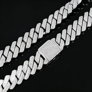 Top-down studio closeup of 19mm full iced out prong set rectangular baguette cuban link chain in polished 18K white gold finish, heavy hip hop necklace fully encrusted with flawless VVS simulated diamond stones, featuring fully micro pave iced box clasp, shot on glossy black reflective mirror surface with natural soft chain reflection, premium copper base men’s street bling hiphop jewelry RDRIP JEWELRY
