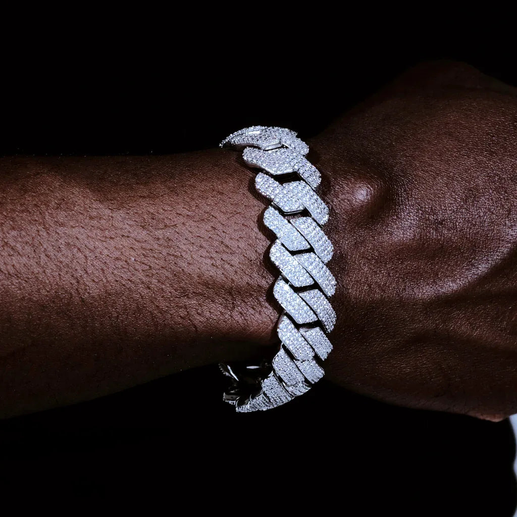 Dark skin male wrist shot wearing oversized 19mm full iced out prong cuban link bracelet, fully encrusted flawless VVS lab tested simulated diamonds all over links and clasp, premium 18K white gold plated solid copper unisex hip hop bling wrist chain, heavy thick statement streetwear jewelry with ultra icy shine hand prong set craftsmanship RDRIP JEWELRY
