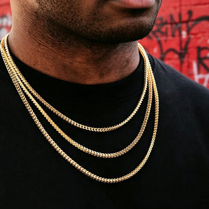 3mm 18k Gold Plated Franco Link Chain layered stacked necklace for men unisex hip hop streetwear jewelry, three different length Franco chains worn on black plain tee, dark skin male model shot against vibrant red graffiti wall background, polished shiny gold Italian design tangle resistant Franco link chain, classic layered hip hop bling necklace from RDRIP JEWELRY, perfect stacking gold chain pendant compatible everyday statement jewelry for street fashion lovers
