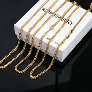 3mm 18k Gold Plated Italian Franco Link Chain multi size product display, multiple polished shiny gold Franco necklaces laid over branded white RDRIP JEWELRY jewelry box printed with SINCE 2016, smooth solid black reflective mirror background, flexible tangle resistant unisex hip hop stacking chain, available in 18 20 24 inch lengths, durable tarnish-free gold streetwear bling compatible with custom pendants, close-up studio product shot of classic layered statement necklace for men and women, premium hand-