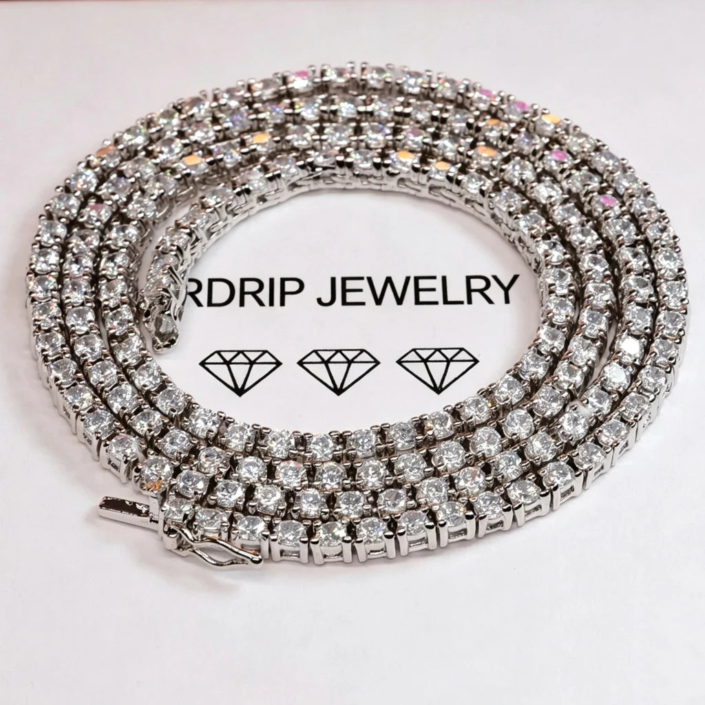Macro close‑up shot of 3MM prong‑set iced out tennis chain necklace, sparkling VVS grade CZ simulated diamonds showing brilliant fire and shine, coiled on branded RDRIP JEWELRY white paper surface, unisex hip‑hop bling jewelry for men and women, RDRIP JEWELRY
