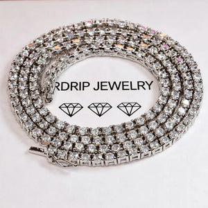 Macro close‑up shot of 3MM prong‑set iced out tennis chain necklace, sparkling VVS grade CZ simulated diamonds showing brilliant fire and shine, coiled on branded RDRIP JEWELRY white paper surface, unisex hip‑hop bling jewelry for men and women, RDRIP JEWELRY
