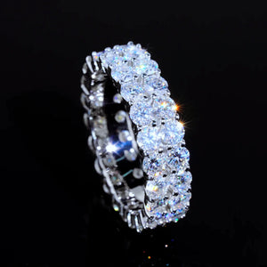 45‑degree angled close‑up view of 6mm double‑row full pave moissanite eternity ring, hand‑set D‑Color VVS1+ 4mm round hearts‑and‑arrows moissanite gemstones, high polished 925 sterling silver white gold plated icy hip‑hop unisex ring, bright star‑burst sparkles and vivid rainbow fire effects against solid dark black background, premium bling statement jewelry for men women RDRIP JEWELRY SINCE 2016
