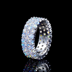 45‑degree tilted profile shot of iced‑out 3‑row cluster eternity ring, D‑color VVS1+ hearts and arrows moissanite stones professionally hand‑set, genuine 925 sterling silver white gold plated band, showing inner hollow ring structure, brilliant multi‑colored light fire and sparkle, hip‑hop unisex luxury bling band ring, reflected on glossy black mirror background against pure dark backdrop, premium statement fashion jewelry RDRIP JEWELRY
