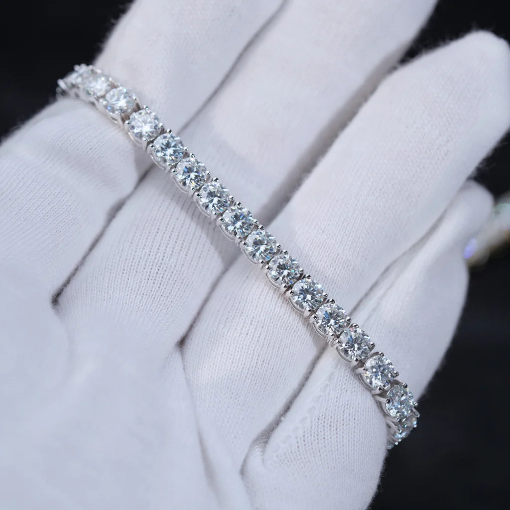 Soft close-up studio shot of 4mm round brilliant D Color VVS1+ clarity moissanite tennis bracelet crafted with solid S925 sterling silver and thick 18K white gold plating, every flawless moissanite stone securely hand prong set by professional artisans, bracelet gently rested on clean soft white cotton jewelry gloves, dark blurred out-of-focus background highlighting icy silvery shine and intense rainbow fire sparkle of each colorless moissanite gem, unisex minimalist iced out hip hop wrist chain suitable f