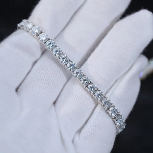 Soft close-up studio shot of 4mm round brilliant D Color VVS1+ clarity moissanite tennis bracelet crafted with solid S925 sterling silver and thick 18K white gold plating, every flawless moissanite stone securely hand prong set by professional artisans, bracelet gently rested on clean soft white cotton jewelry gloves, dark blurred out-of-focus background highlighting icy silvery shine and intense rainbow fire sparkle of each colorless moissanite gem, unisex minimalist iced out hip hop wrist chain suitable f