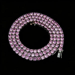 4mm Aurora Rainbow Iced Tennis Chain coiled top angle view, pastel pink purple blue ombre gradient VVS simulated CZ diamonds, hand prong‑set round stones, visible metal lock clasp, brilliant starburst shine, 18K gold plated unisex hip hop bling necklace on solid black background, RDRIP JEWELRY
