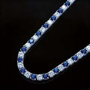 Macro close‑up shot of 4mm Iced Out Blue and White Alternating Tennis Chain, detailed view of hand‑prong‑set VVS sapphire‑blue and white round simulated diamonds, two‑tone hip hop bling necklace on pure black reflective display surface RDRIP JEWELRY
