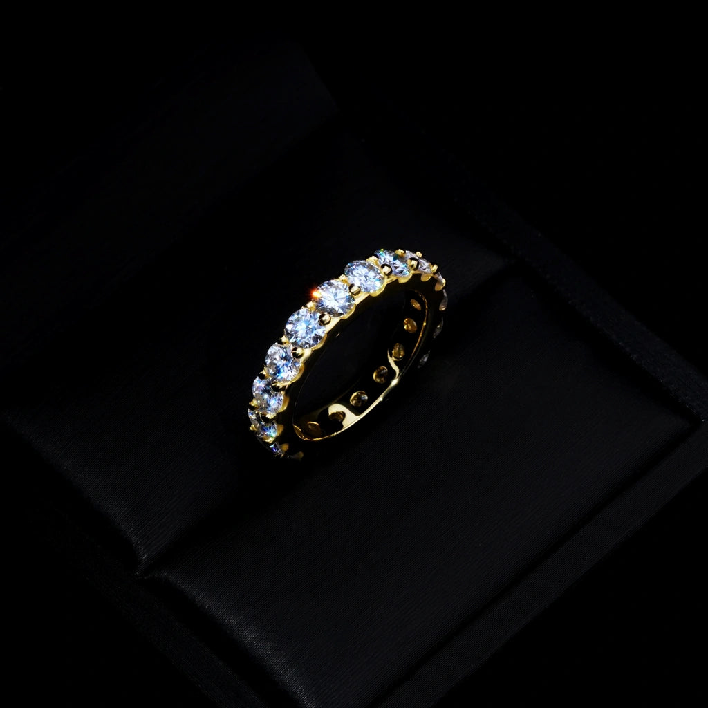 6.00 CARAT S925 VVS1+ moissanite single‑row full eternity ring, 4mm round ideal cut hearts and arrows moissanite stones, 18K gold plated genuine 925 sterling silver band, golden icy sparkling full circle band ring placed inside luxury black satin jewelry gift box, dark moody studio close‑up shot, brilliant light sparkle, unisex hip‑hop wedding engagement stackable fine bling jewelry RDRIP JEWELRY