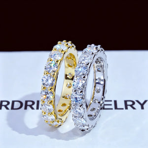 6.00 CARAT S925 VVS1+ moissanite single‑row full eternity ring, 4mm round ideal cut hearts and arrows moissanite stones, standing side‑by‑side display of 18K gold‑plated and white gold‑plated genuine 925 sterling silver bands, upright two rings close‑up product shot, icy brilliant sparkling full circle band rings laid on RDRIP JEWELRY branded white background, unisex hip‑hop wedding matching stackable fine bling jewelry RDRIP JEWELRY