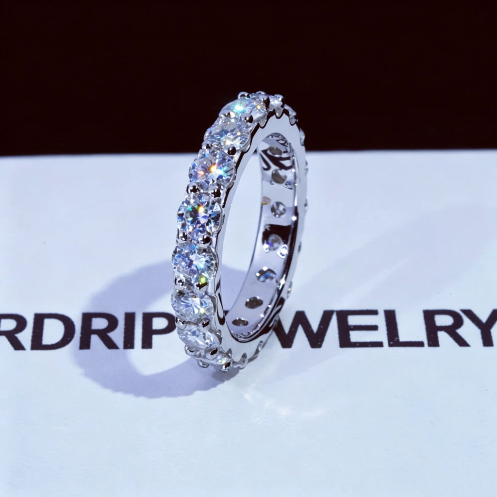 6.00 CARAT S925 VVS1+ moissanite single‑row full eternity ring, 4mm round ideal cut hearts and arrows moissanite stones, white gold plated genuine 925 sterling silver band, icy brilliant sparkling full circle band ring, single ring side view close‑up shot, displayed on RDRIP JEWELRY branded printed white surface, unisex hip‑hop wedding stackable fine bling jewelry dark background product photography RDRIP JEWELRY